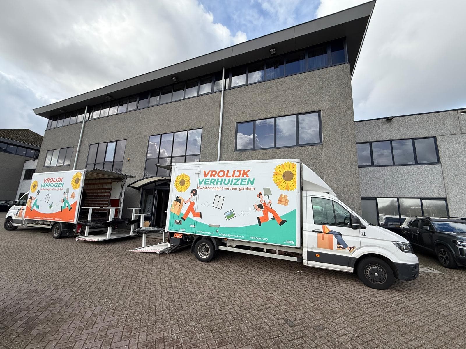 Several Vrolijk Verhuizen vans outside a business premises