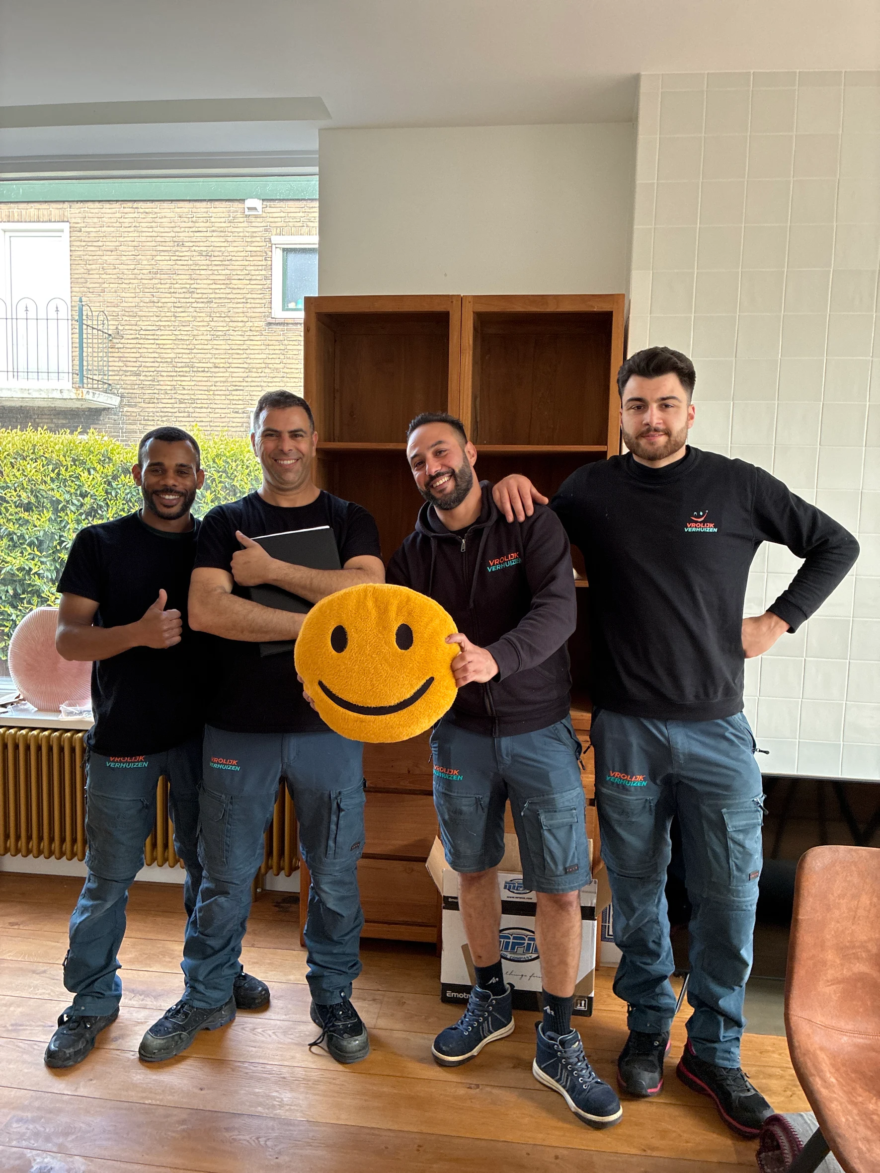 Four Vrolijk Verhuizen crew members with the smiley that captures their motto