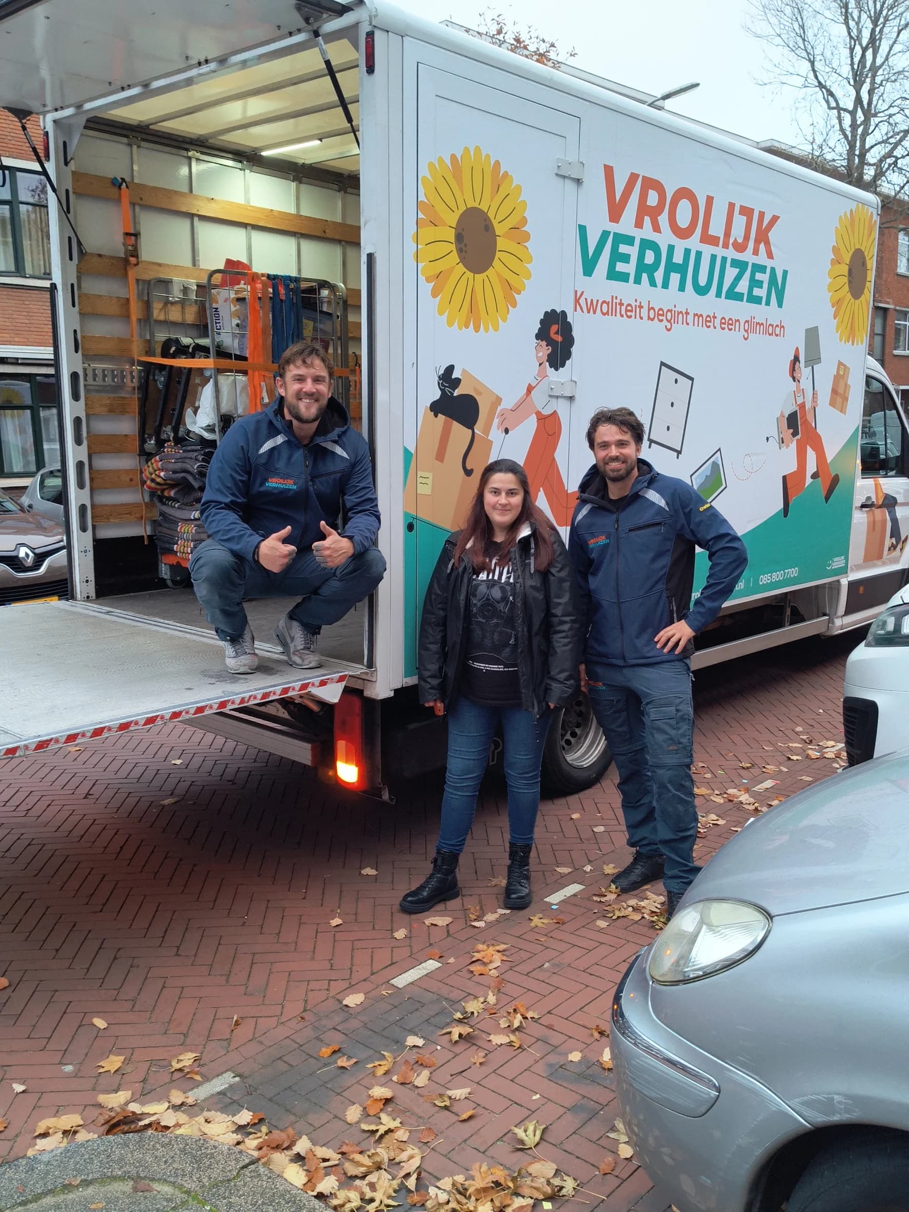Two Vrolijk Verhuizen crew members with a happy customer at the tail lift