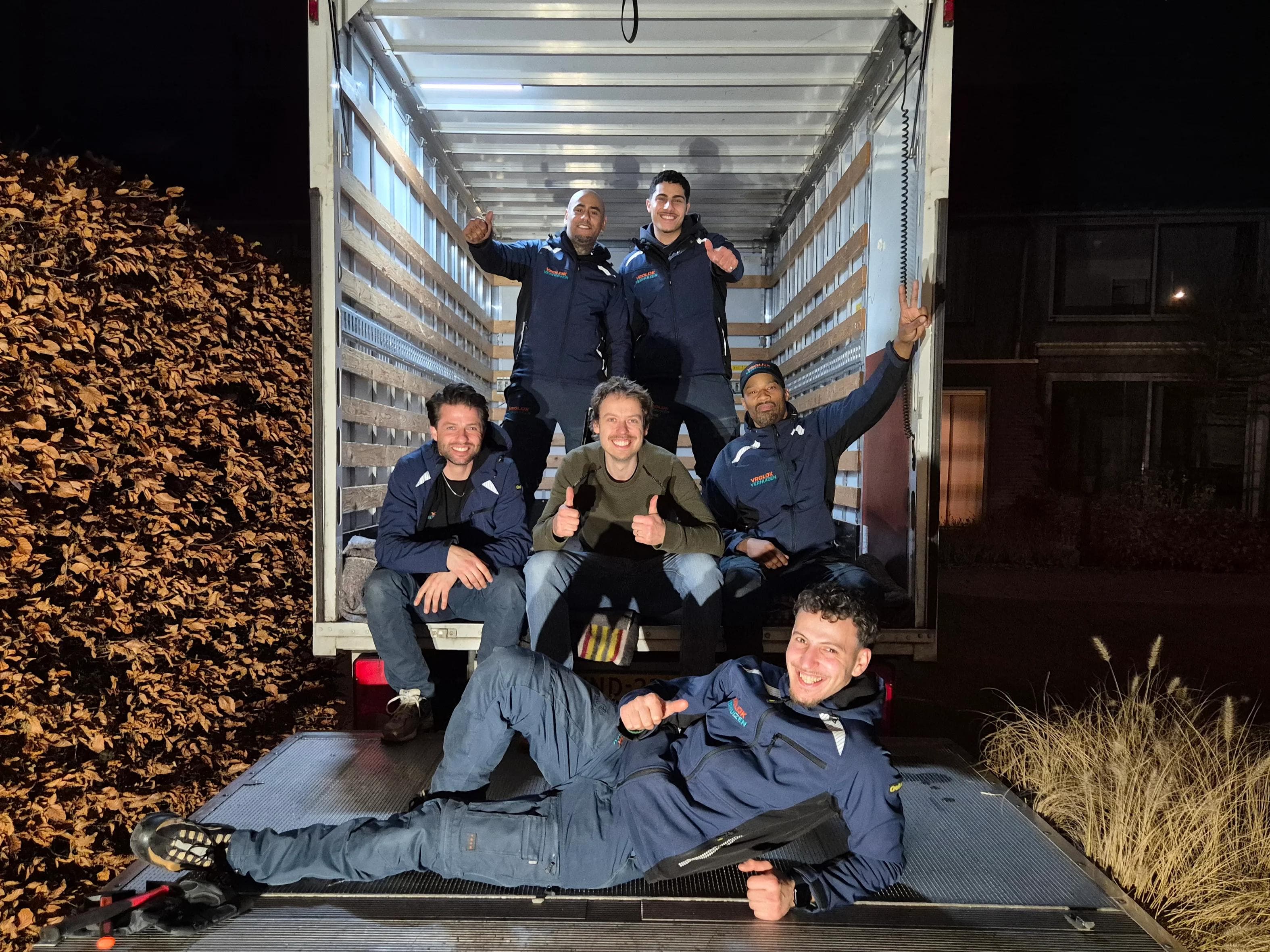 Vrolijk Verhuizen team met een tevreden klant naast de bus